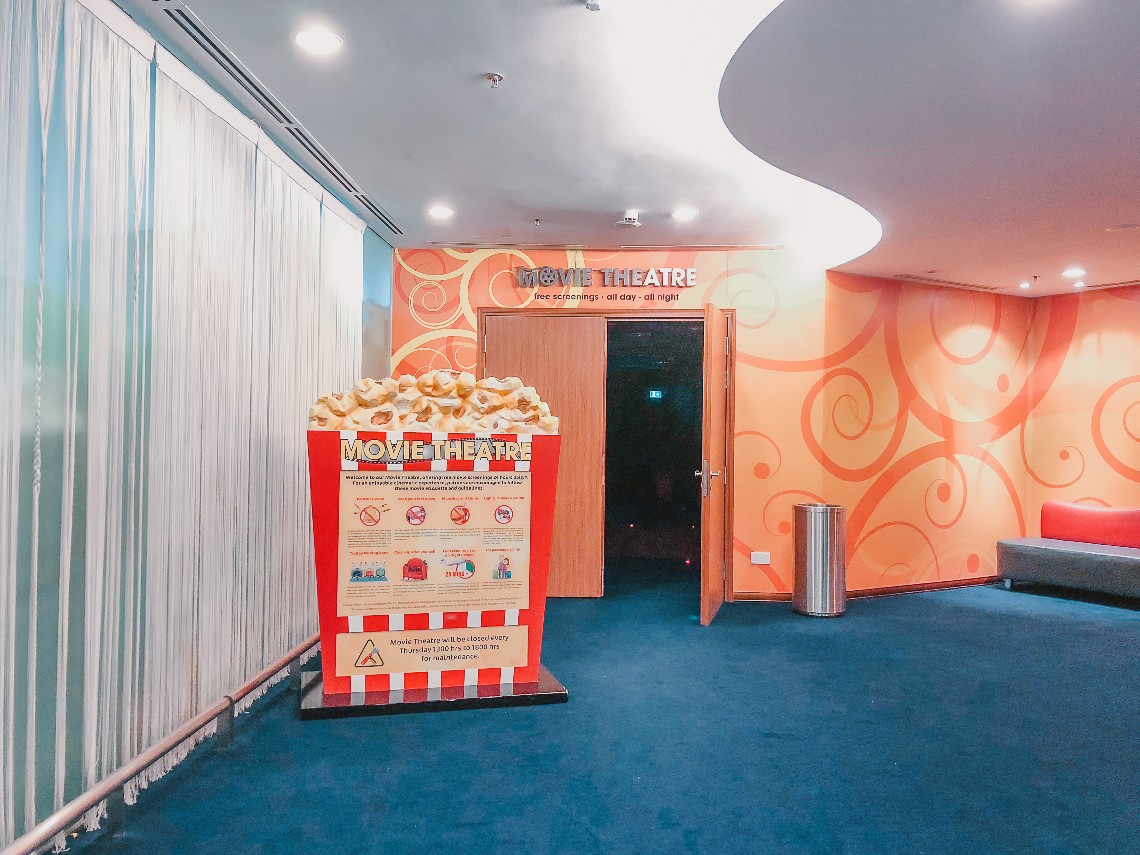 Movie theatre with orange exterior and a big popcorn structure at the entrance 